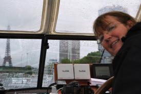 Nuala steering the boat past the Eiffel Tower in the rain
